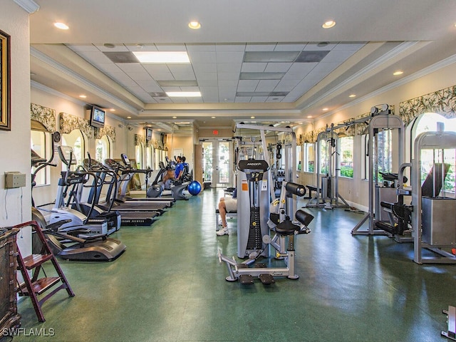 exercise room featuring a paneled ceiling, a raised ceiling, crown molding, and french doors