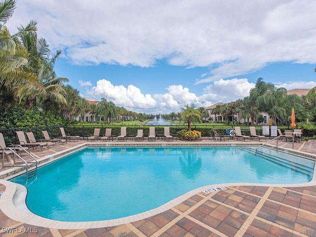 pool with a patio area and fence