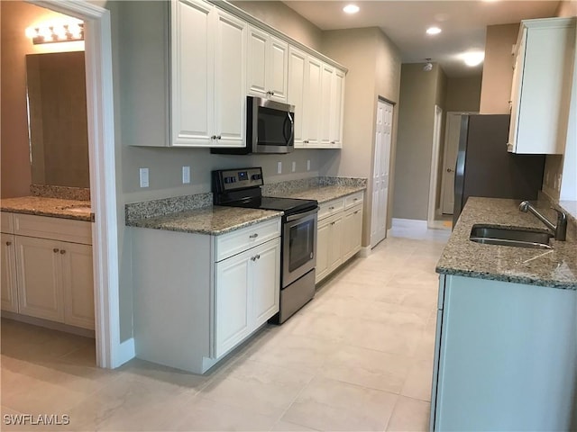 kitchen featuring sink, stainless steel appliances, white cabinetry, and stone countertops