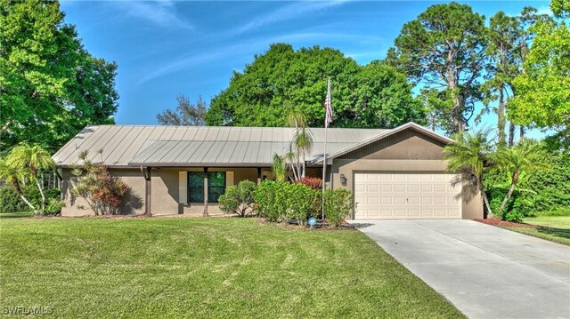 ranch-style home with a garage, driveway, metal roof, a front lawn, and stucco siding