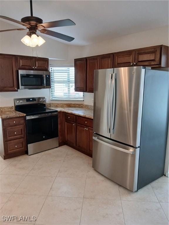 kitchen with light stone countertops, stainless steel appliances, ceiling fan, and light tile patterned floors