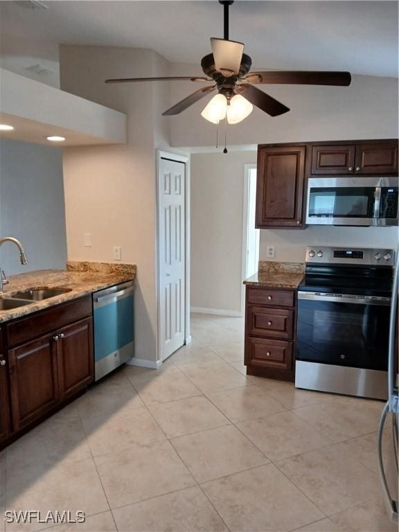 kitchen with sink, stainless steel appliances, light stone counters, and light tile patterned floors