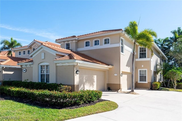 mediterranean / spanish house featuring a garage, concrete driveway, a tile roof, and stucco siding