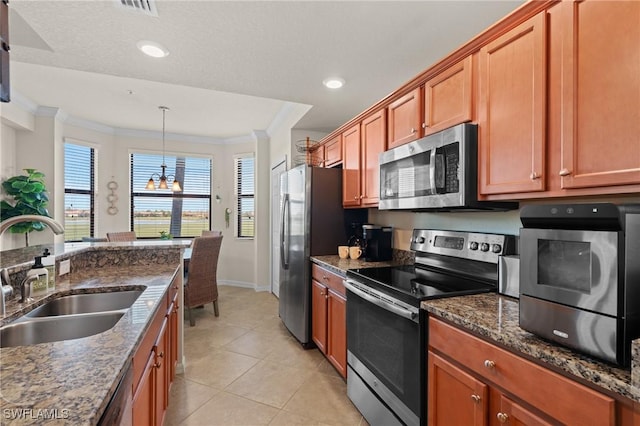 kitchen with appliances with stainless steel finishes, ornamental molding, dark stone countertops, decorative light fixtures, and a sink