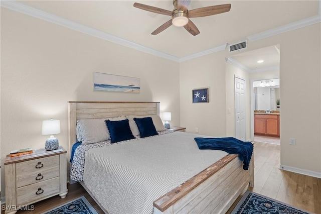 bedroom with baseboards, visible vents, ensuite bath, crown molding, and light wood-type flooring