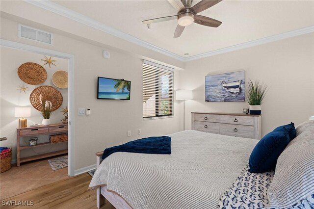 bedroom with light wood-type flooring, visible vents, crown molding, and baseboards