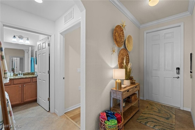 foyer with light tile patterned floors, baseboards, visible vents, and crown molding