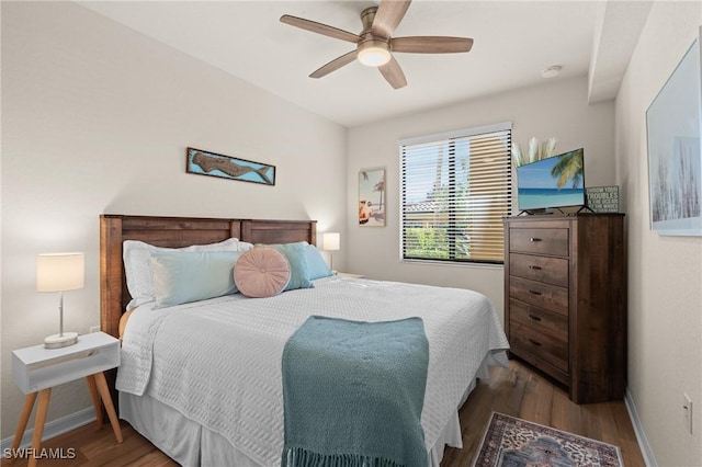 bedroom featuring ceiling fan, baseboards, and wood finished floors