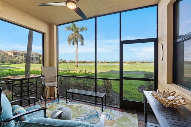 sunroom featuring golf course view and a ceiling fan