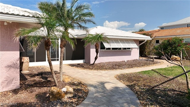 ranch-style house featuring a tiled roof and stucco siding