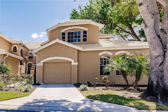 view of front of home with stucco siding, an attached garage, and driveway