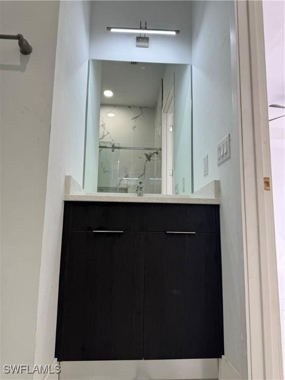 bathroom featuring vanity and a marble finish shower