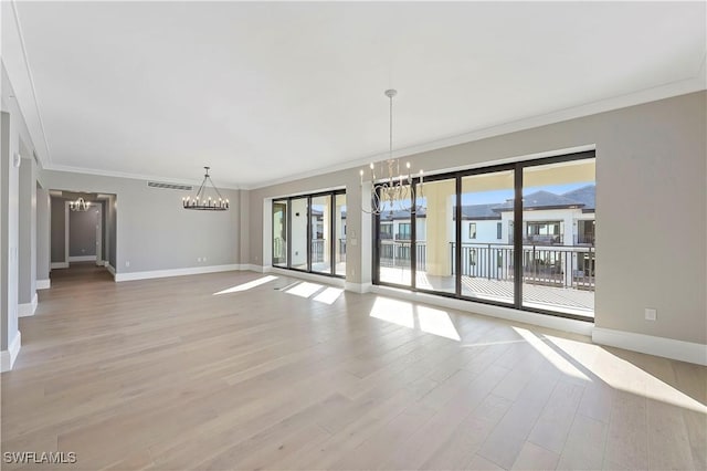 spare room featuring ornamental molding, light hardwood / wood-style flooring, and a chandelier