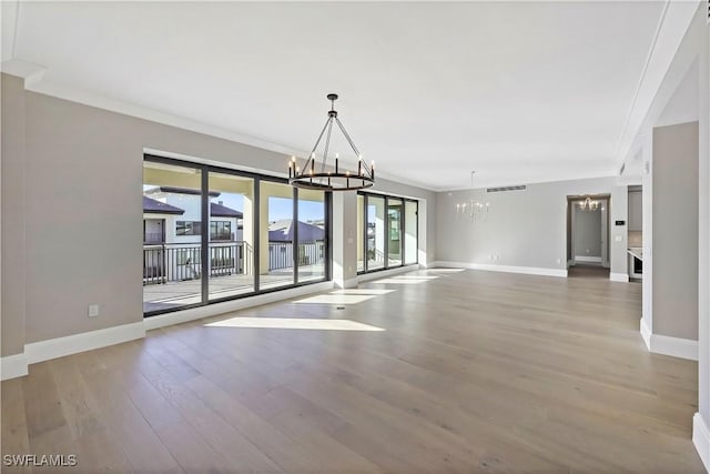 unfurnished dining area featuring hardwood / wood-style floors, a chandelier, and ornamental molding