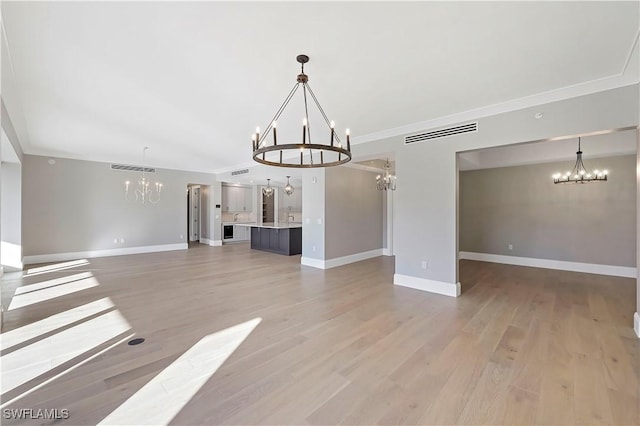 interior space with a notable chandelier, light wood-type flooring, and crown molding