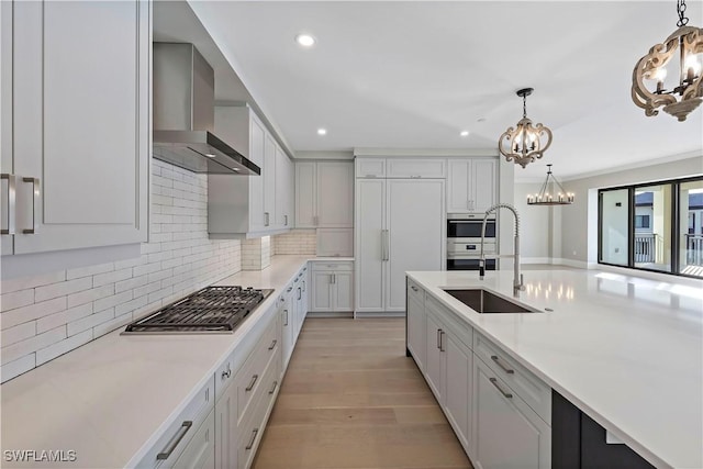 kitchen featuring sink, white cabinetry, wall chimney exhaust hood, and decorative light fixtures