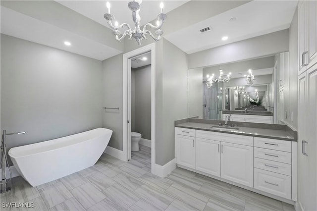 bathroom with a notable chandelier, a bath, toilet, and vanity