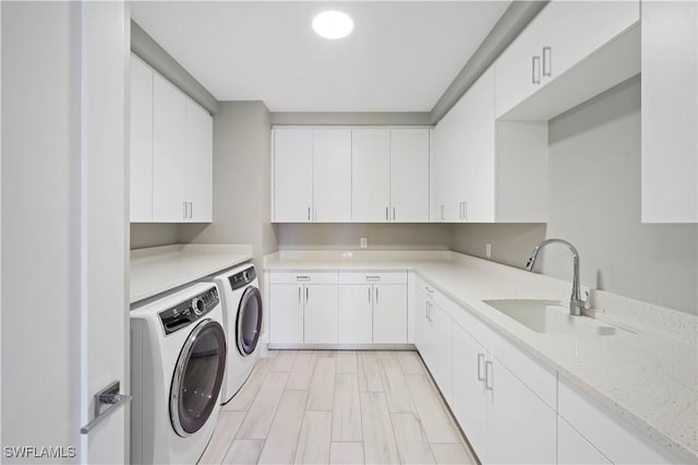 washroom with sink, independent washer and dryer, and cabinets