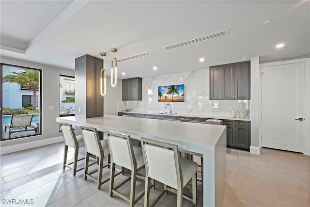 kitchen featuring hanging light fixtures, a center island, tasteful backsplash, light tile patterned floors, and a breakfast bar area