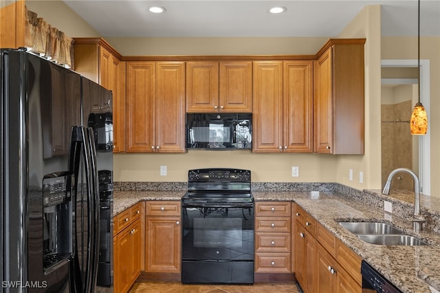 kitchen featuring light stone counters, a sink, hanging light fixtures, brown cabinets, and black appliances