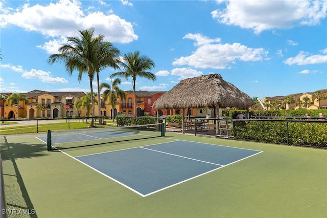 view of tennis court featuring a residential view, fence, and a gazebo