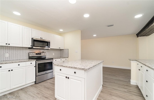 kitchen featuring appliances with stainless steel finishes, white cabinetry, a kitchen island, and decorative backsplash