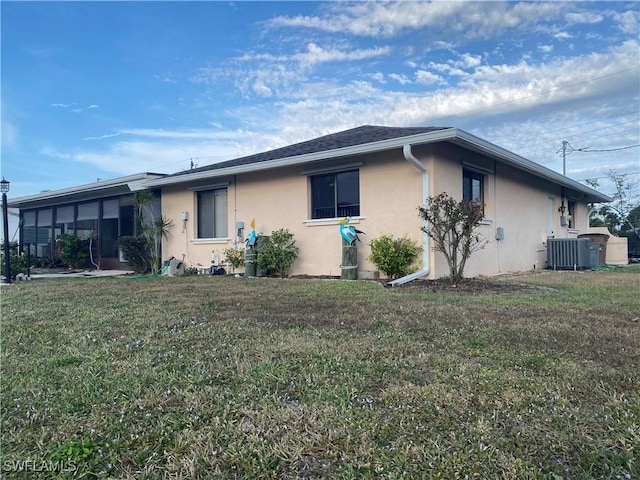 ranch-style house with a front yard, central AC unit, and stucco siding