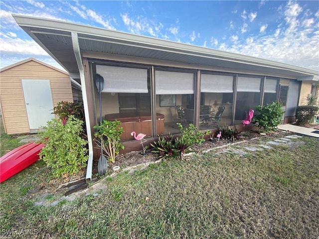 view of side of property with a yard, an outdoor structure, a hot tub, and a storage unit