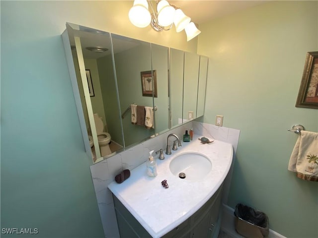 bathroom with a notable chandelier, vanity, and toilet