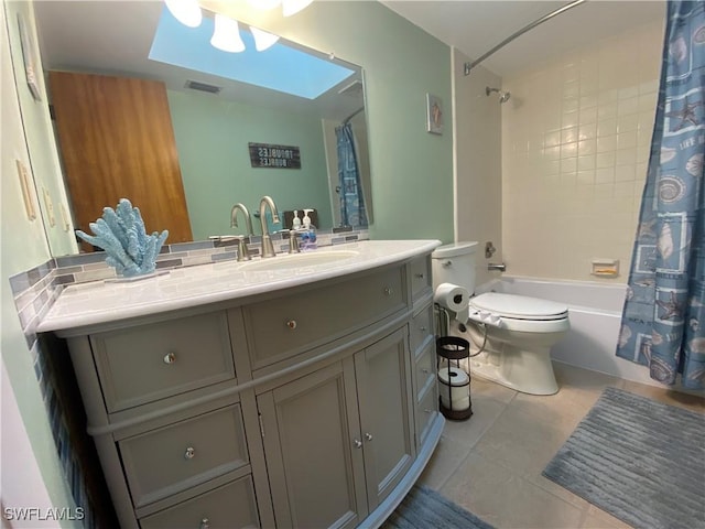 bathroom with a skylight, shower / tub combo with curtain, toilet, vanity, and tile patterned floors