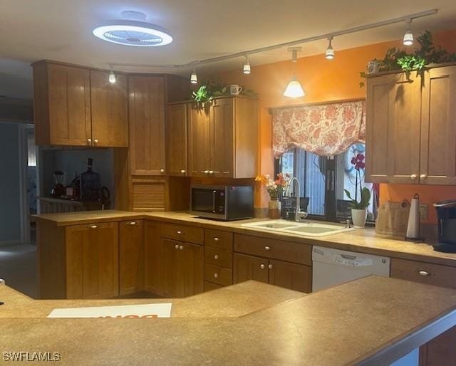 kitchen with light countertops, pendant lighting, stainless steel microwave, and a sink