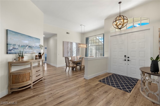 entrance foyer featuring a chandelier, visible vents, light wood-style flooring, and baseboards