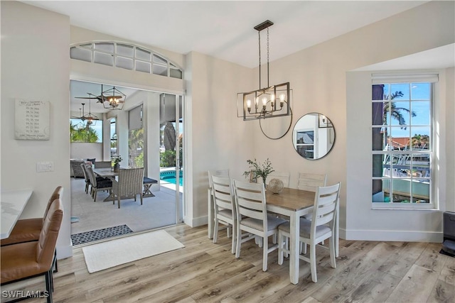 dining space featuring baseboards, light wood finished floors, and a notable chandelier