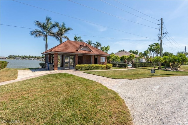 view of front of property with a front yard, french doors, a tile roof, and a water view