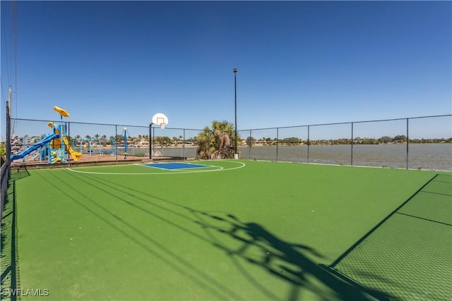 view of property's community with community basketball court, playground community, a water view, and fence