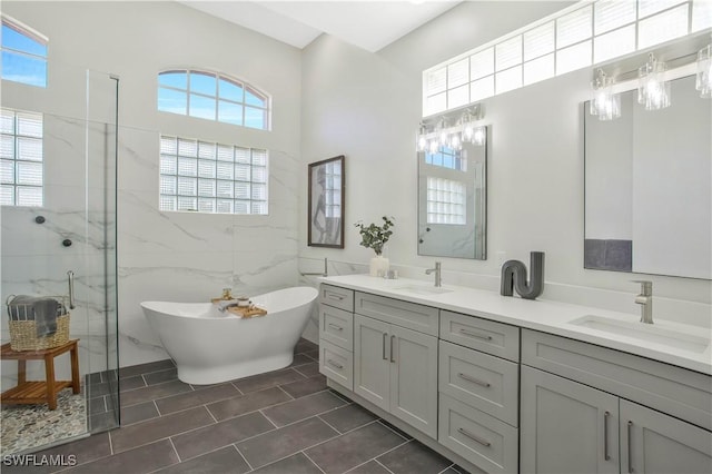 full bath featuring double vanity, a soaking tub, a sink, and tile walls