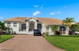 single story home with decorative driveway and a front lawn