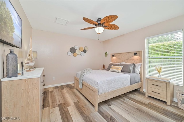 bedroom featuring light wood-style floors, visible vents, baseboards, and ceiling fan