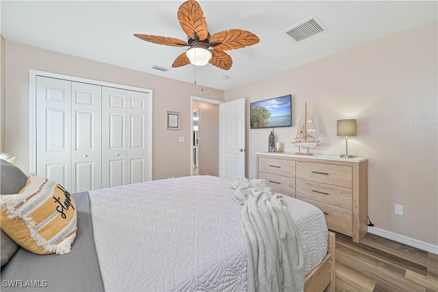 bedroom featuring a closet, visible vents, a ceiling fan, wood finished floors, and baseboards