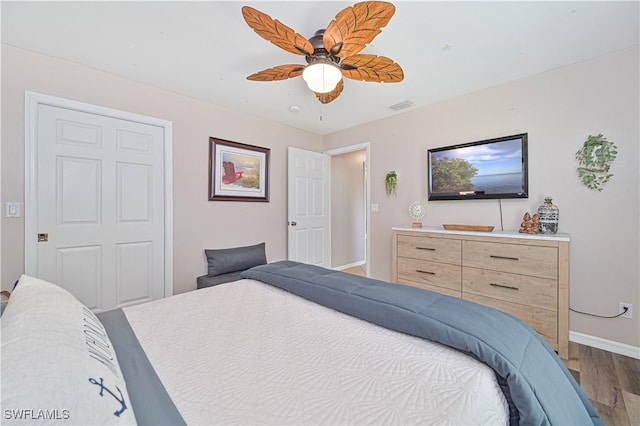 bedroom featuring visible vents, ceiling fan, baseboards, and wood finished floors