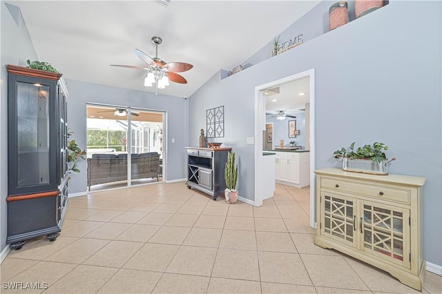 living area featuring light tile patterned floors, baseboards, vaulted ceiling, and a ceiling fan