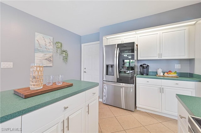 kitchen featuring white cabinets, stove, stainless steel refrigerator with ice dispenser, and light tile patterned flooring