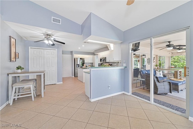 kitchen with light tile patterned floors, appliances with stainless steel finishes, lofted ceiling, and white cabinetry