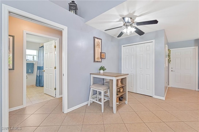 interior space with ceiling fan, baseboards, and light tile patterned flooring