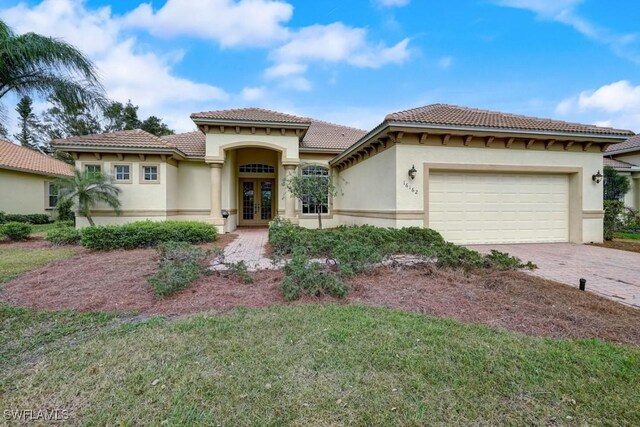 mediterranean / spanish-style house featuring a front lawn, french doors, and a garage