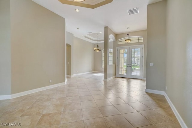 entrance foyer with a raised ceiling, french doors, an inviting chandelier, and light tile patterned floors