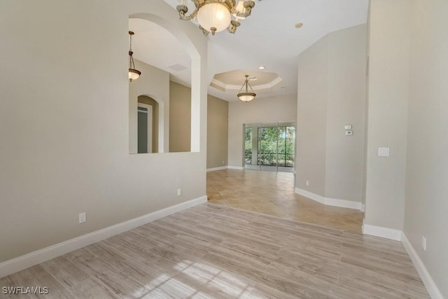 empty room with a raised ceiling and light hardwood / wood-style flooring