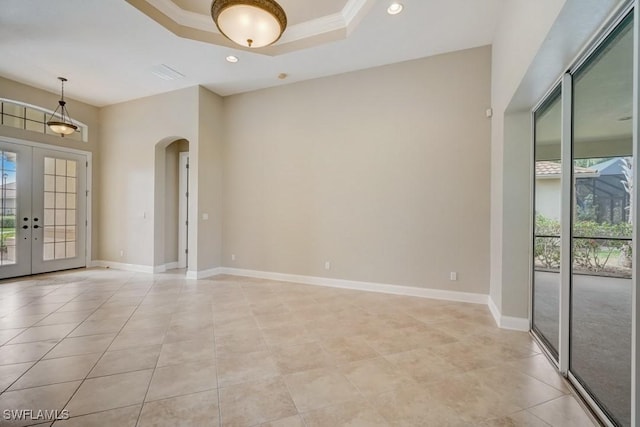 tiled empty room featuring a tray ceiling, crown molding, and french doors