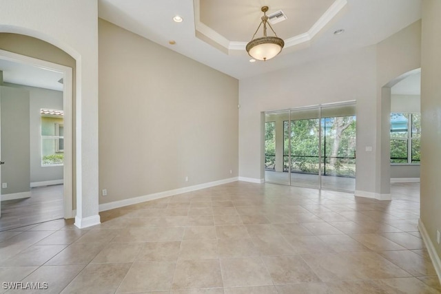 tiled empty room with a raised ceiling and a towering ceiling