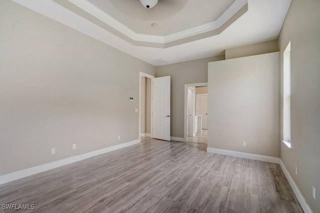 unfurnished bedroom with light hardwood / wood-style flooring, crown molding, and a raised ceiling